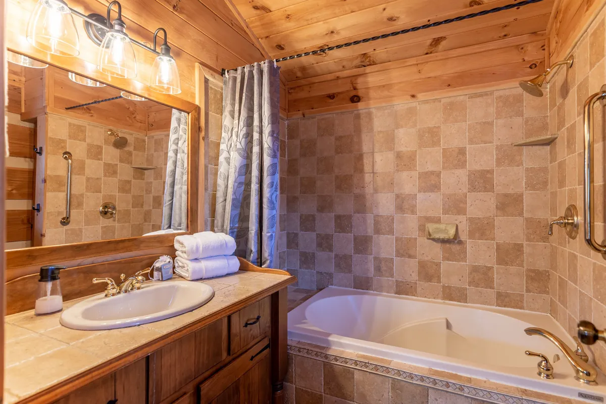 A tranquil bathroom featuring a standalone soaking tub, vanity with a sink, wooden cabinetry, and a decorative mirror. Soft lighting enhances the spa-like atmosphere, ideal for relaxation after a busy day.